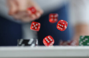 Man throws red dice on table and chips. Casino game and luck